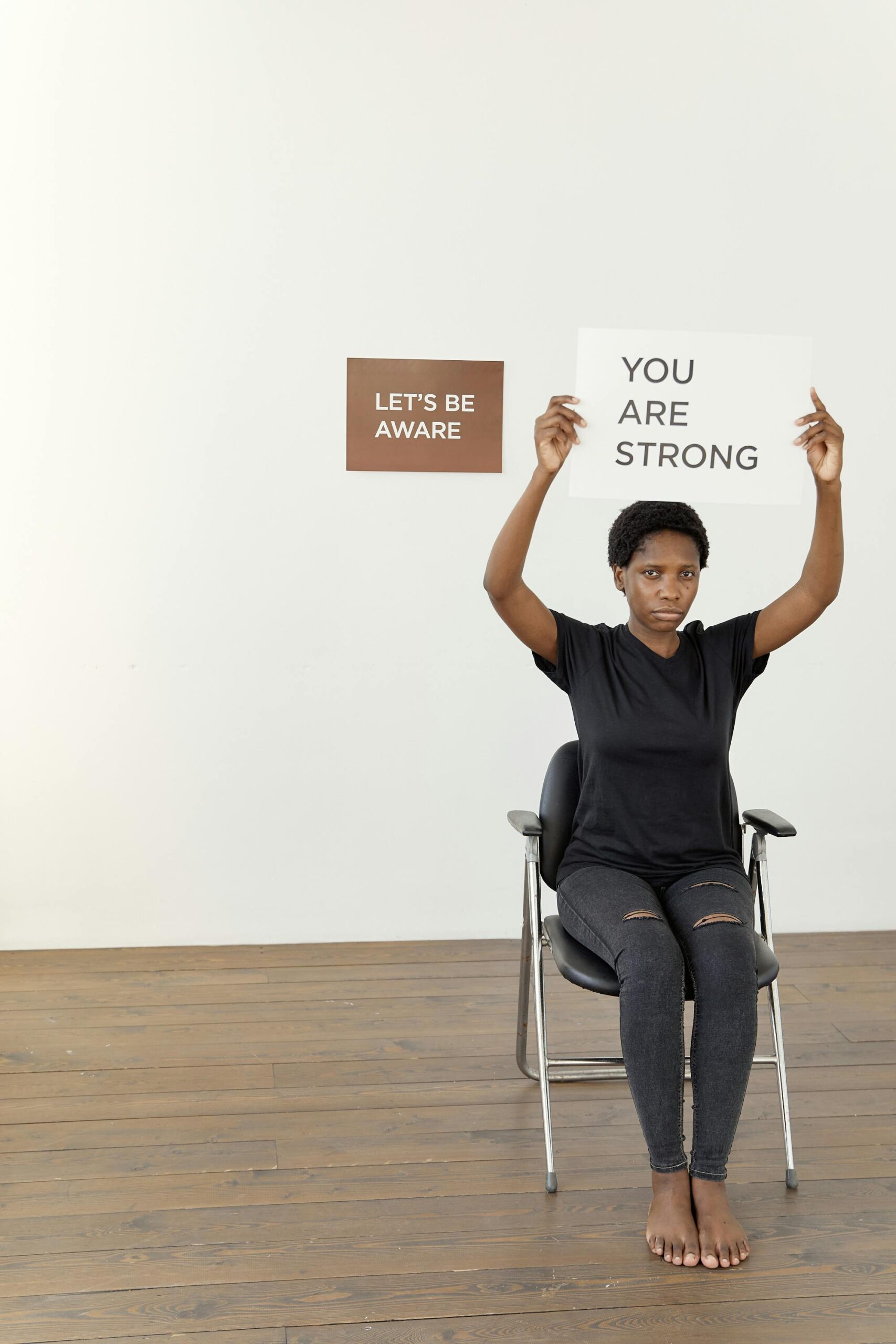 Black woman holding a sign with an empowering message, advocating awareness and strength.
